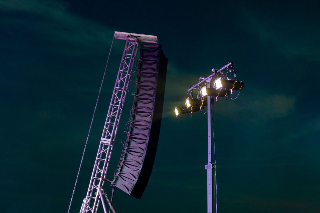 Image of a concert speaker and stage lighting setup under the night sky.