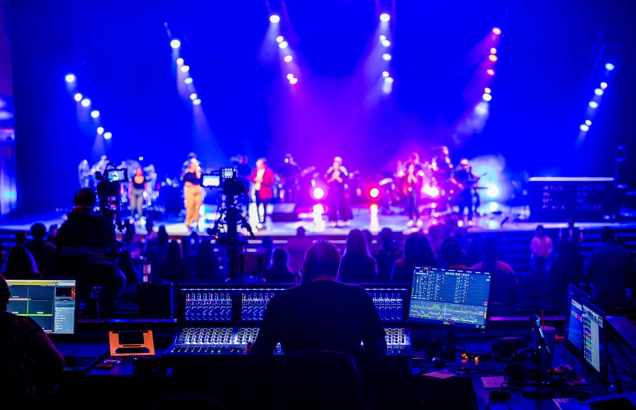 Sound engineer at a vibrant live concert with bright stage lights and audience.